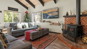 A cozy living room with a fireplace, a sofa, a rug, and a Christmas tree.