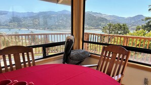 A balcony with a table and chairs, overlooking a scenic view of mountains and a bridge. - Fantastic River & Ocean Views! Family Friendly Home, Sleeps 8 (Gold Beach)