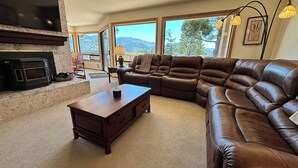 A living room with a sectional sofa, a fireplace, and large windows offering a view of the outdoors. - Fantastic River & Ocean Views! Family Friendly Home, Sleeps 8 (Gold Beach)