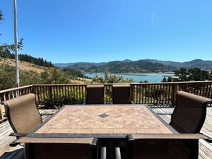 Une terrasse avec une table et des chaises, d’où l’on a vue sur un lac et des montagnes.
