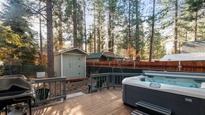 Eine Holzterrasse mit Whirlpool, Grill und Geräteschuppen.