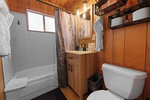 A wooden bathroom with a bathtub, toilet, and sink.