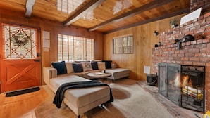 Una sala de estar acogedora con chimenea, paredes de madera y un sofá seccional.