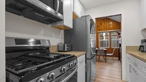 A modern kitchen with stainless steel appliances, a gas stove, and wooden cabinets. - Big Bear Cottage - Walk to Lake, Apple TV, Fireplace, Deck (Big Bear Lake)