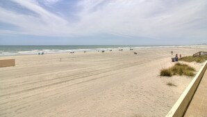 A wide sandy beach with a wooden boardwalk on the right.