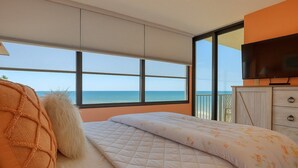 A bedroom with a bed, a TV, and a view of the sea.