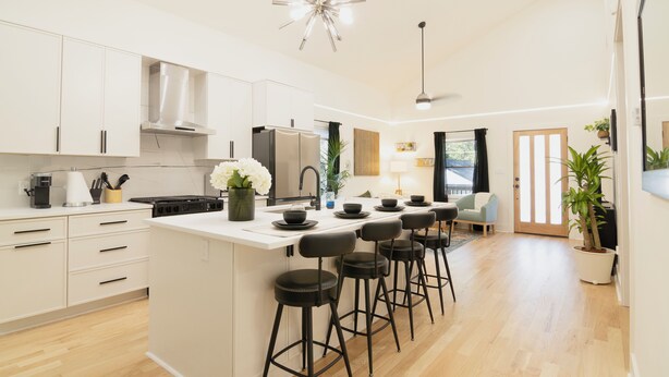 A modern kitchen with white cabinets, a central island with stools, a stainless steel range hood, and a pendant light. - 3-bedroom home in beautiful Atlanta. 10 mins from Mercedes Benz. FIFA World Cup (Atlanta)