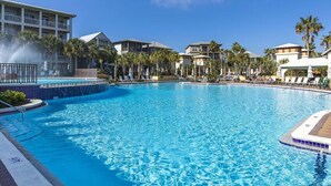Una gran piscina con una fuente, rodeada de palmeras y edificios de hotel.