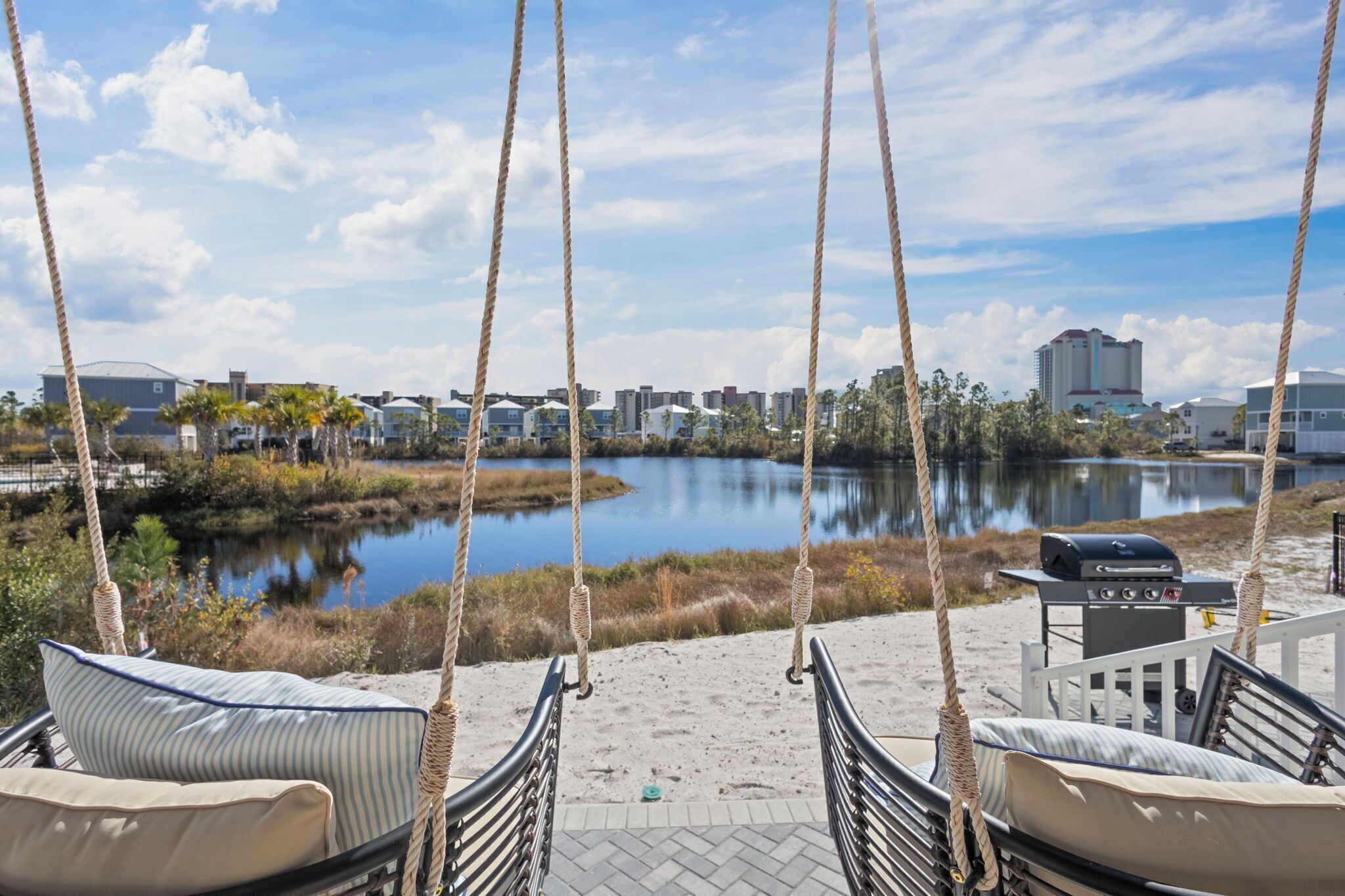 Una silla colgante con vista a un lago, una parrilla y una vista panorámica de la ciudad.