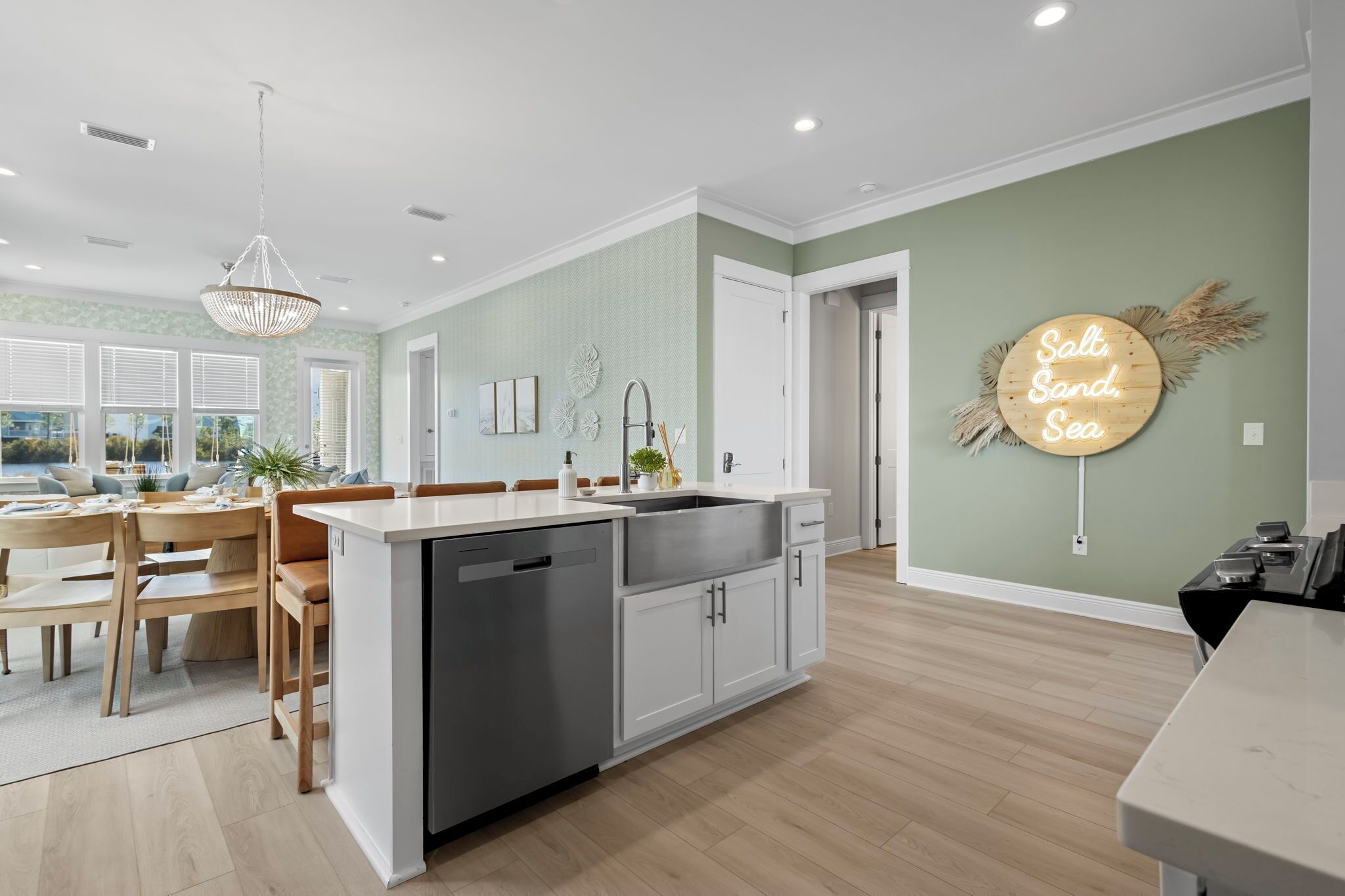 A modern kitchen with a central island, white cabinetry, and a neon sign on the wall.