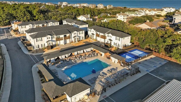 Zona residencial con piscina, varias casas y vista al océano.