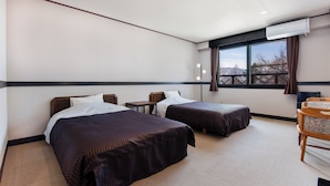 A hotel room with two beds, a desk, a chair, a window with a view, and an air conditioning unit. - Hotel Eldia Madarao (Myoko)
