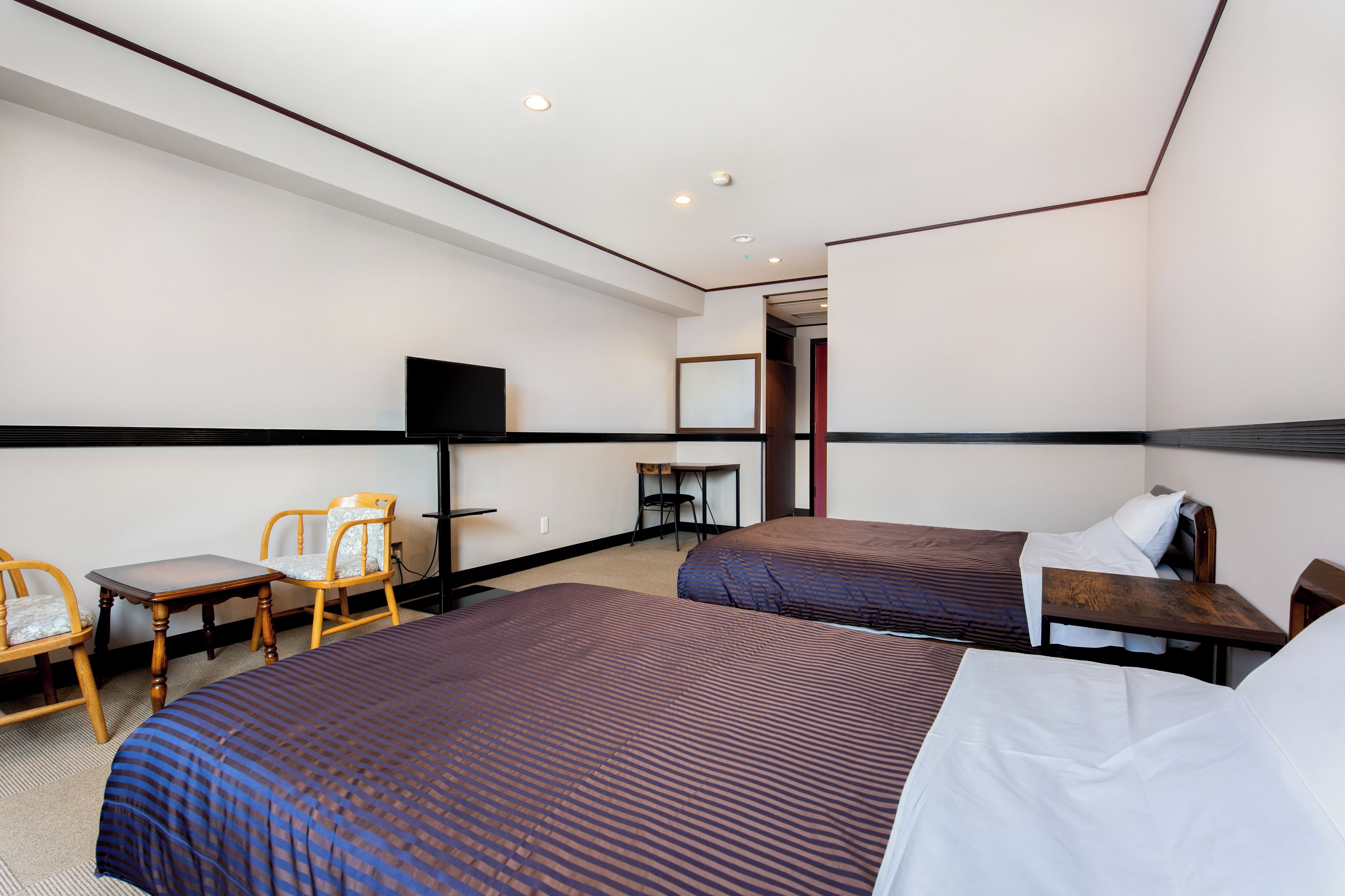 Una habitación de hotel con dos camas, televisión, escritorio y una silla.