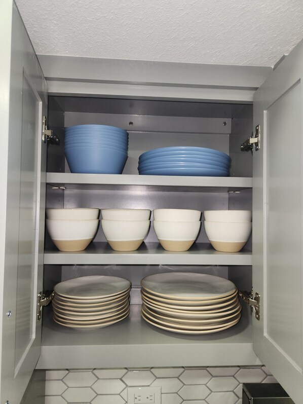 Un armario de cocina con varios estantes que contienen cuencos y platos.
