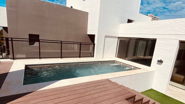 Ein modernes Gebäude mit Pool, einer Holzterrasse und blauem Himmel.