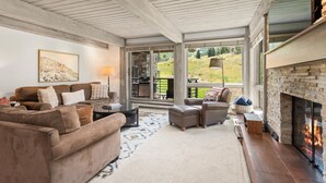 A spacious living room with a fireplace, large windows, and a cozy seating area.