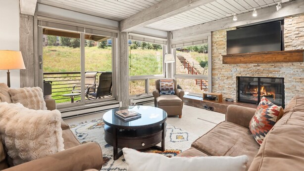 A spacious living room with a fireplace, comfortable seating, and a large TV.