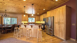 A spacious kitchen with wooden cabinets, a stainless steel refrigerator, and a dining area with a table and chairs. - Charming 4-bedroom house in marvelous Truckee with WiFi, fitness room (Truckee)