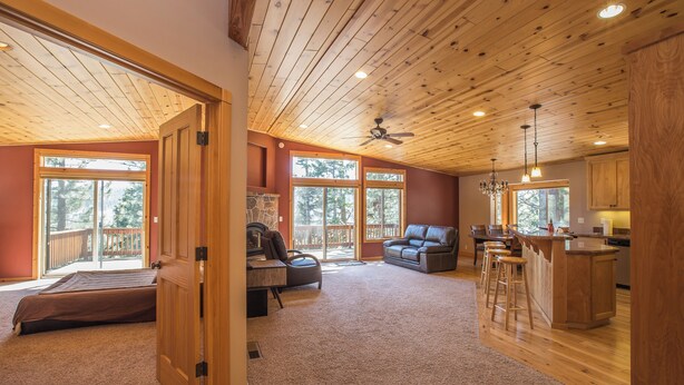 A spacious living area with a large window, a ceiling fan, and a wooden kitchen area. - Charming 4-bedroom house in marvelous Truckee with WiFi, fitness room (Truckee)
