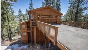 A wooden cabin with a balcony and a garage, surrounded by trees and a clear sky. - Charming 4-bedroom house in marvelous Truckee with WiFi, fitness room (Truckee)