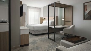 A modern hotel room with a bed, a desk, a chair, and a small table. - Springhill Suites By Marriott Troy Dayton (Troy)