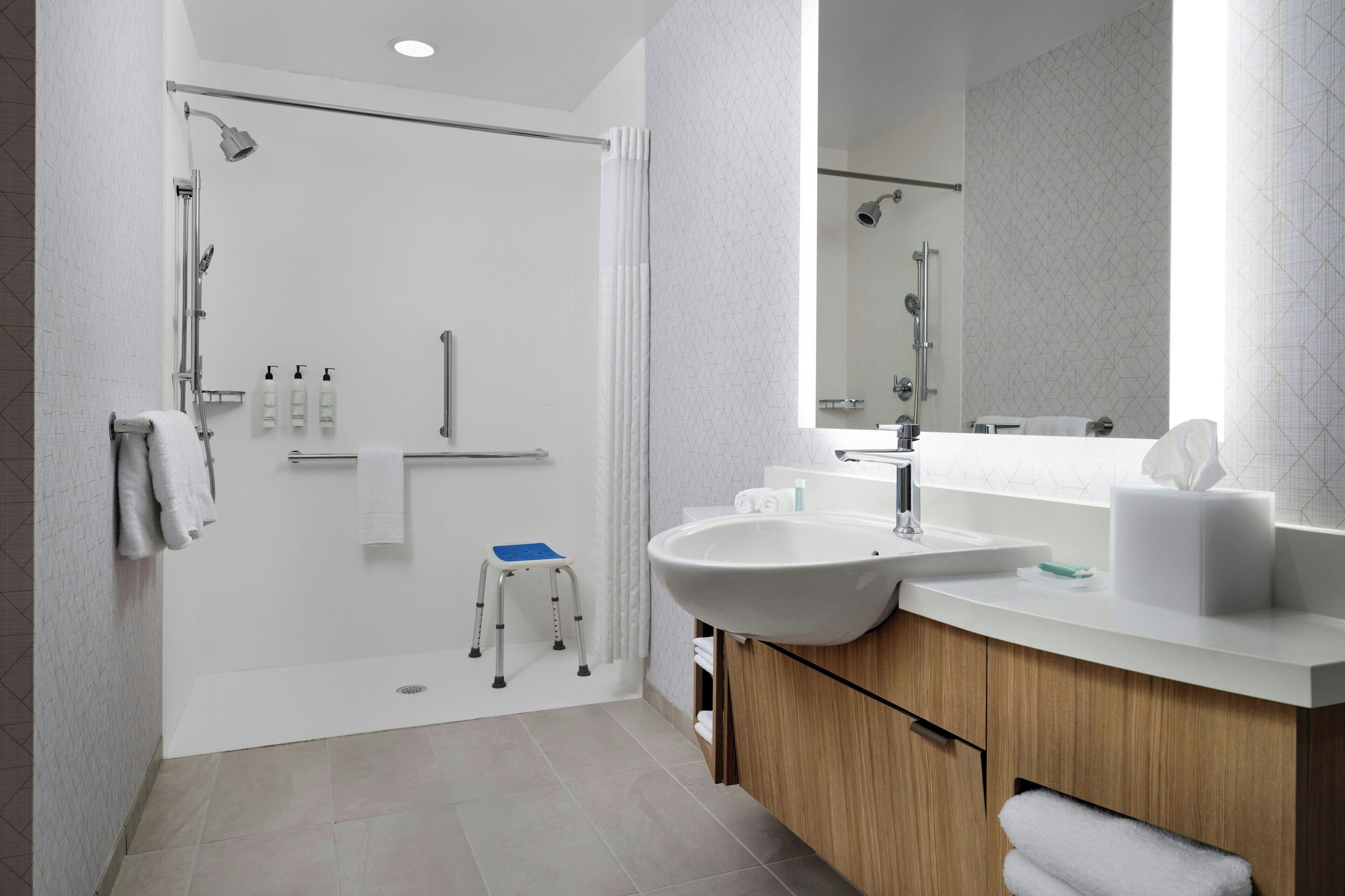 Une salle de bain moderne dotée d’une douche à l’italienne, d’un grand lavabo et d’un meuble-lavabo avec un miroir.