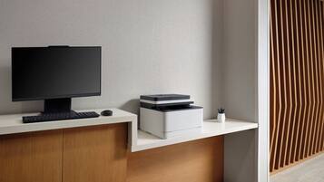 A modern desk with a flat-screen monitor, keyboard, and printer.