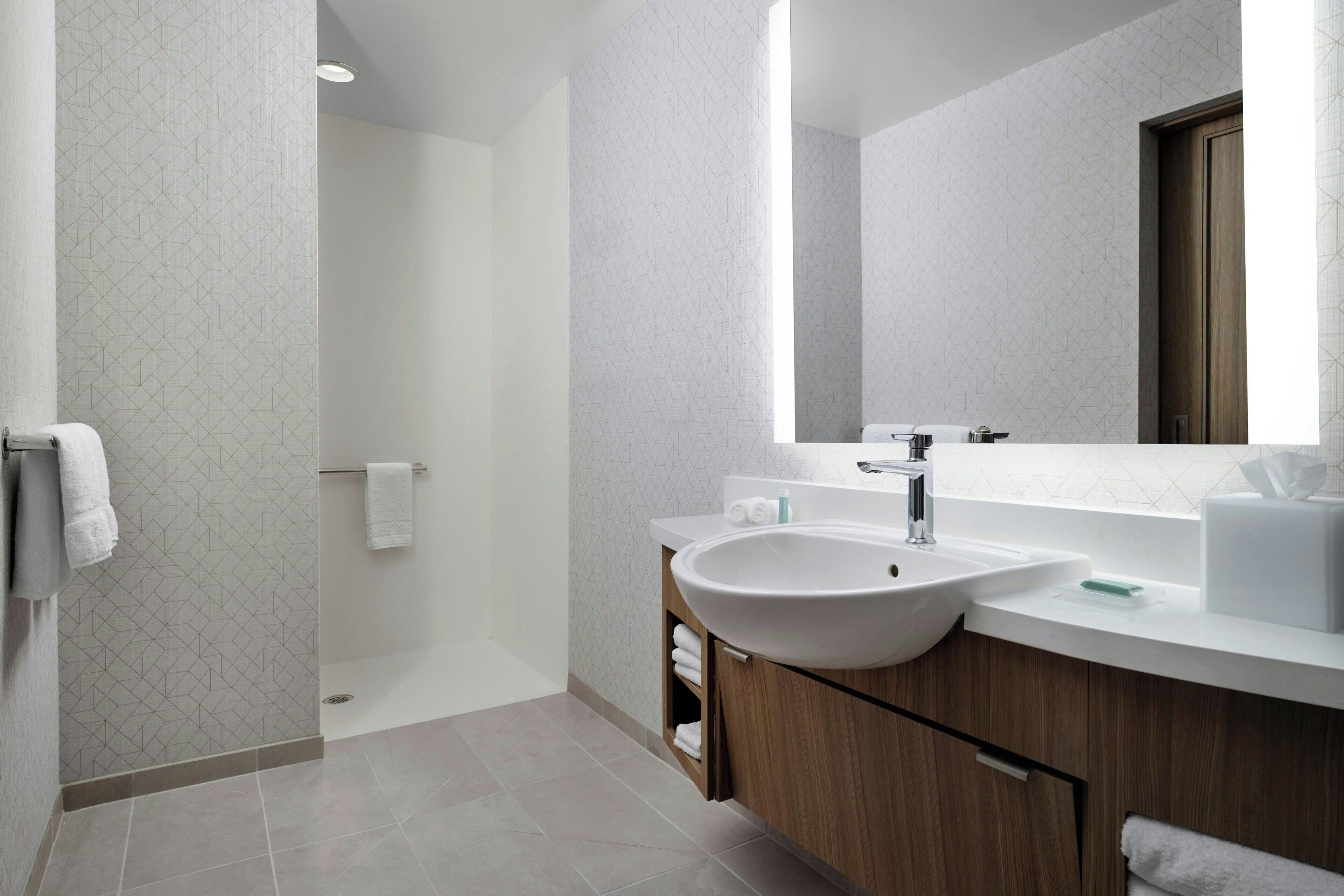 Une salle de bain moderne avec un grand lavabo, un miroir et une douche.