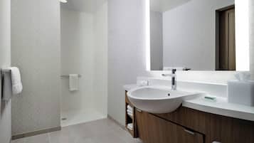 Une salle de bain moderne avec un grand lavabo, un miroir et une douche.