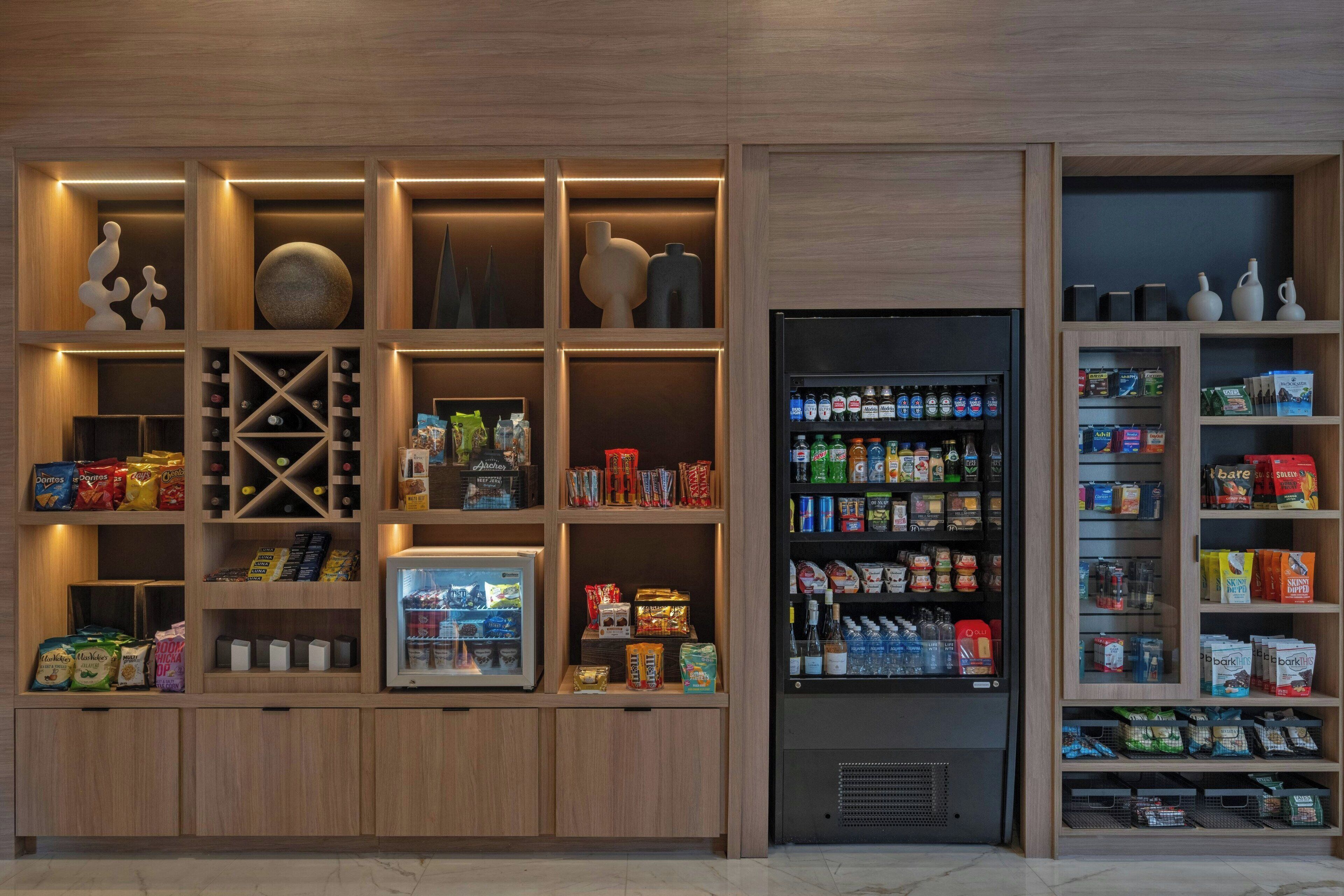 A modern retail space with wooden shelving units displaying snacks, beverages, and household items.