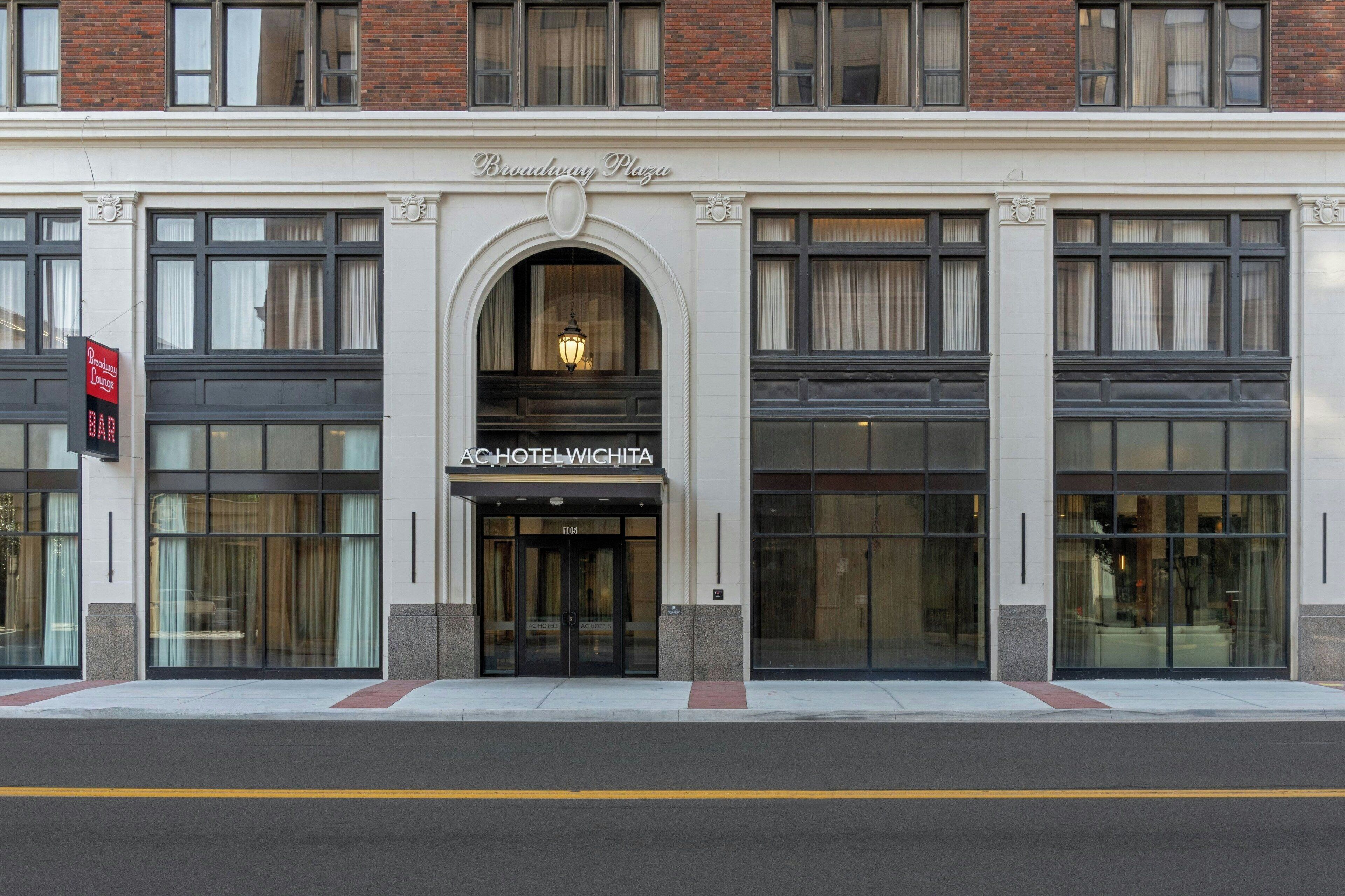 A hotel facade with a central entrance, large windows, and a sign reading "Broadway Plaza."