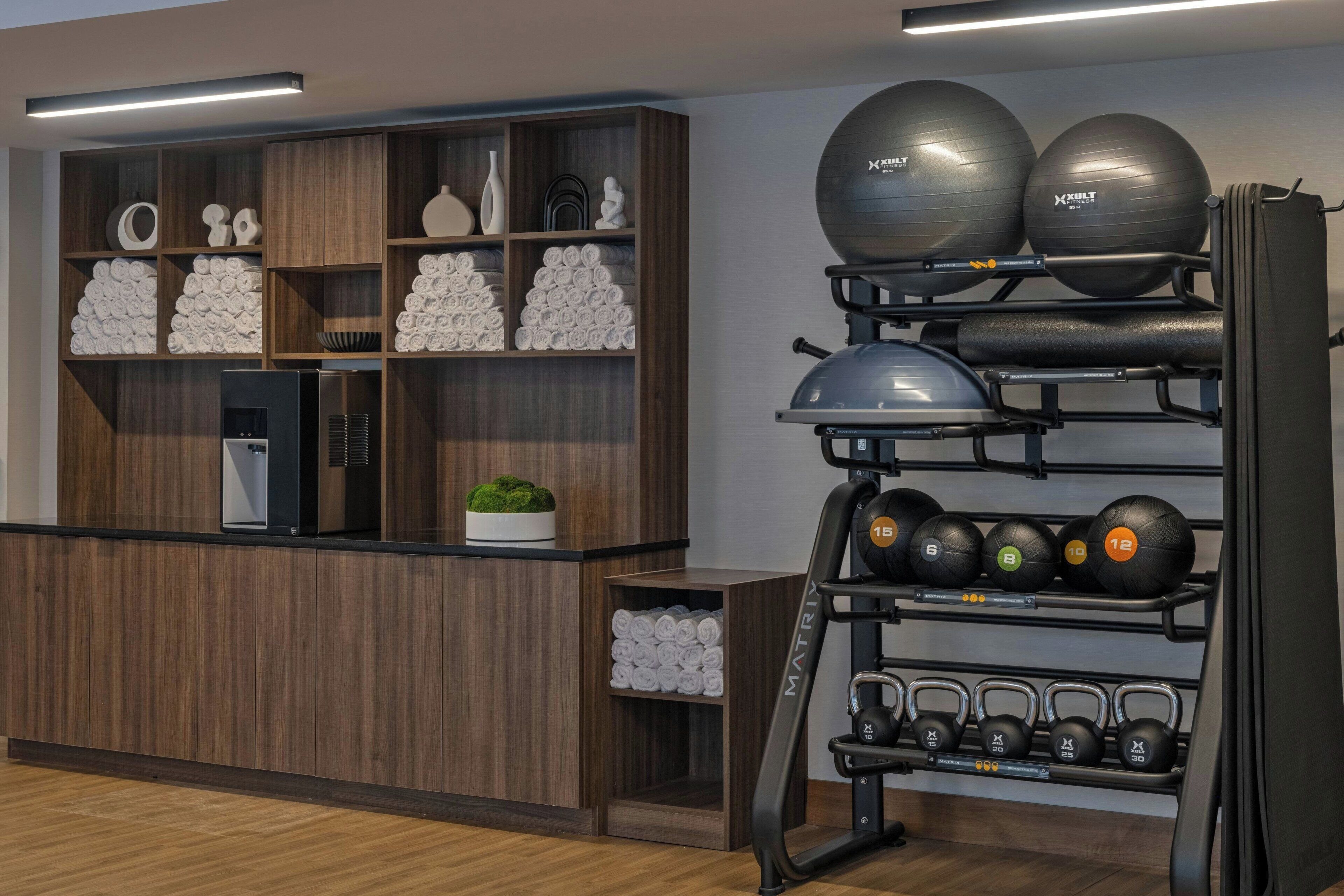 A gym with wooden shelves holding towels, exercise balls, and kettlebells.