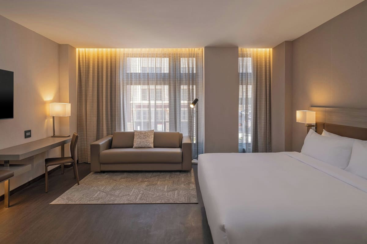 Una habitación de hotel con una cama grande, un sofá, un escritorio y un televisor.
