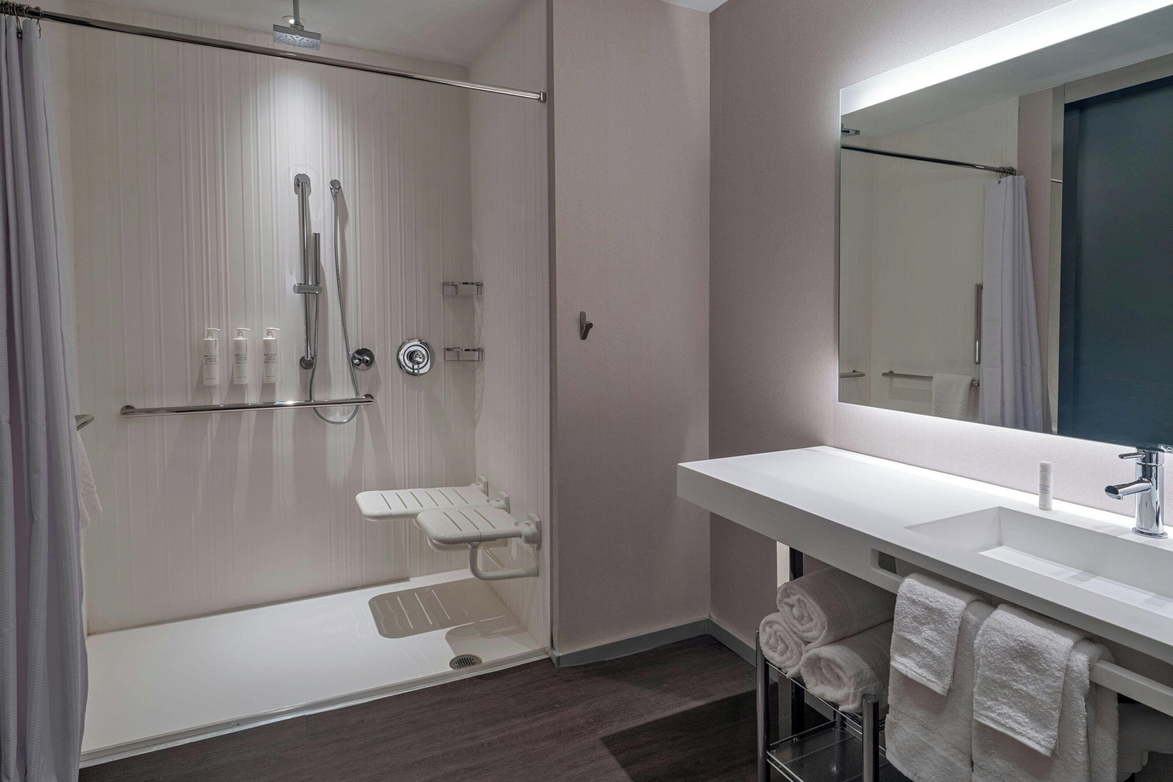 A modern bathroom with a glass-enclosed shower, a white sink, and a large mirror.