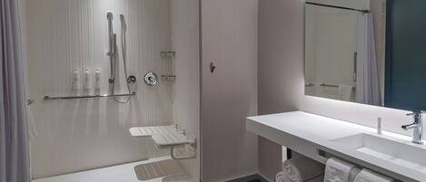 A modern bathroom with a glass-enclosed shower, a white sink, and a large mirror.