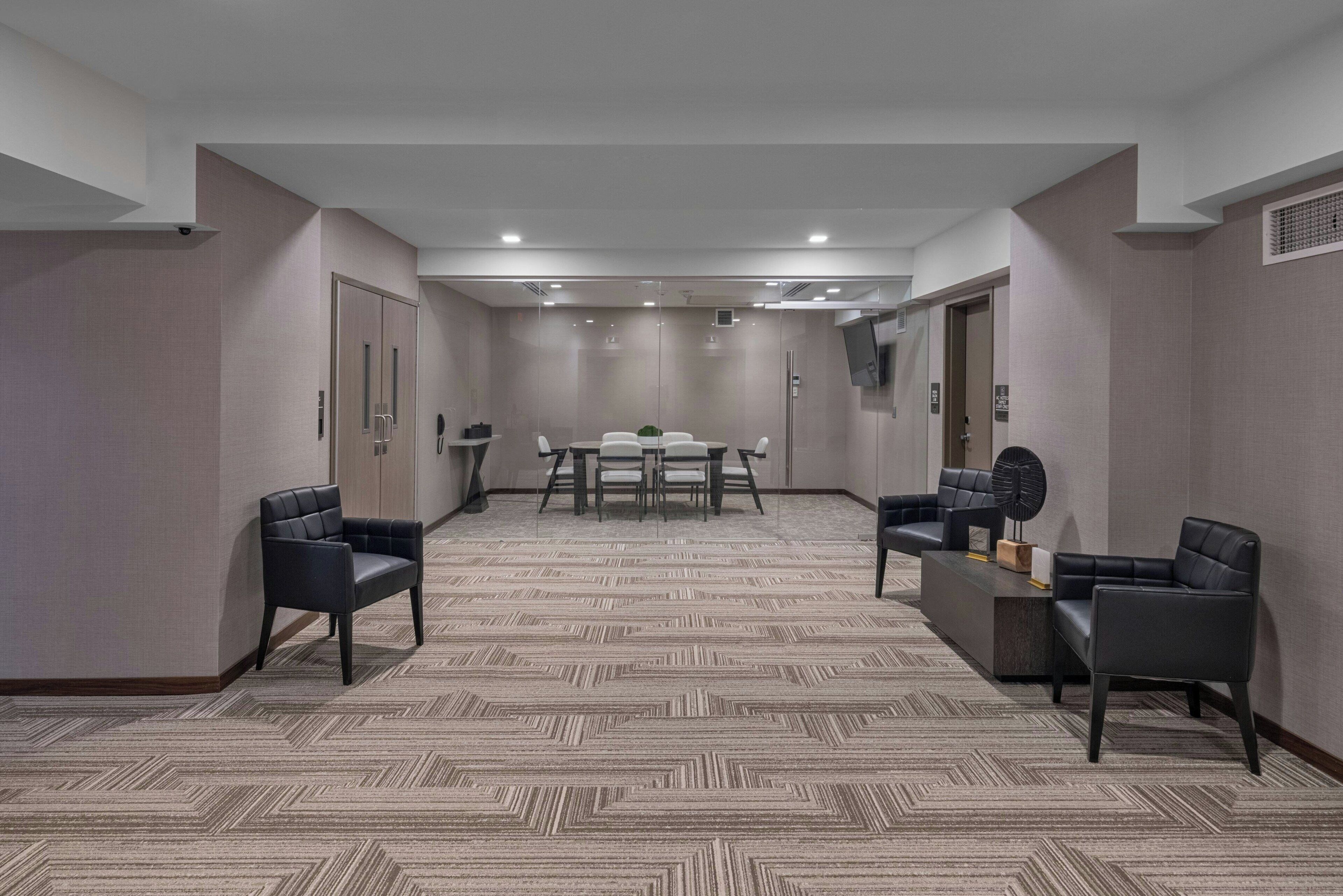 A conference room with a carpeted floor, a table with chairs, and two sofas.
