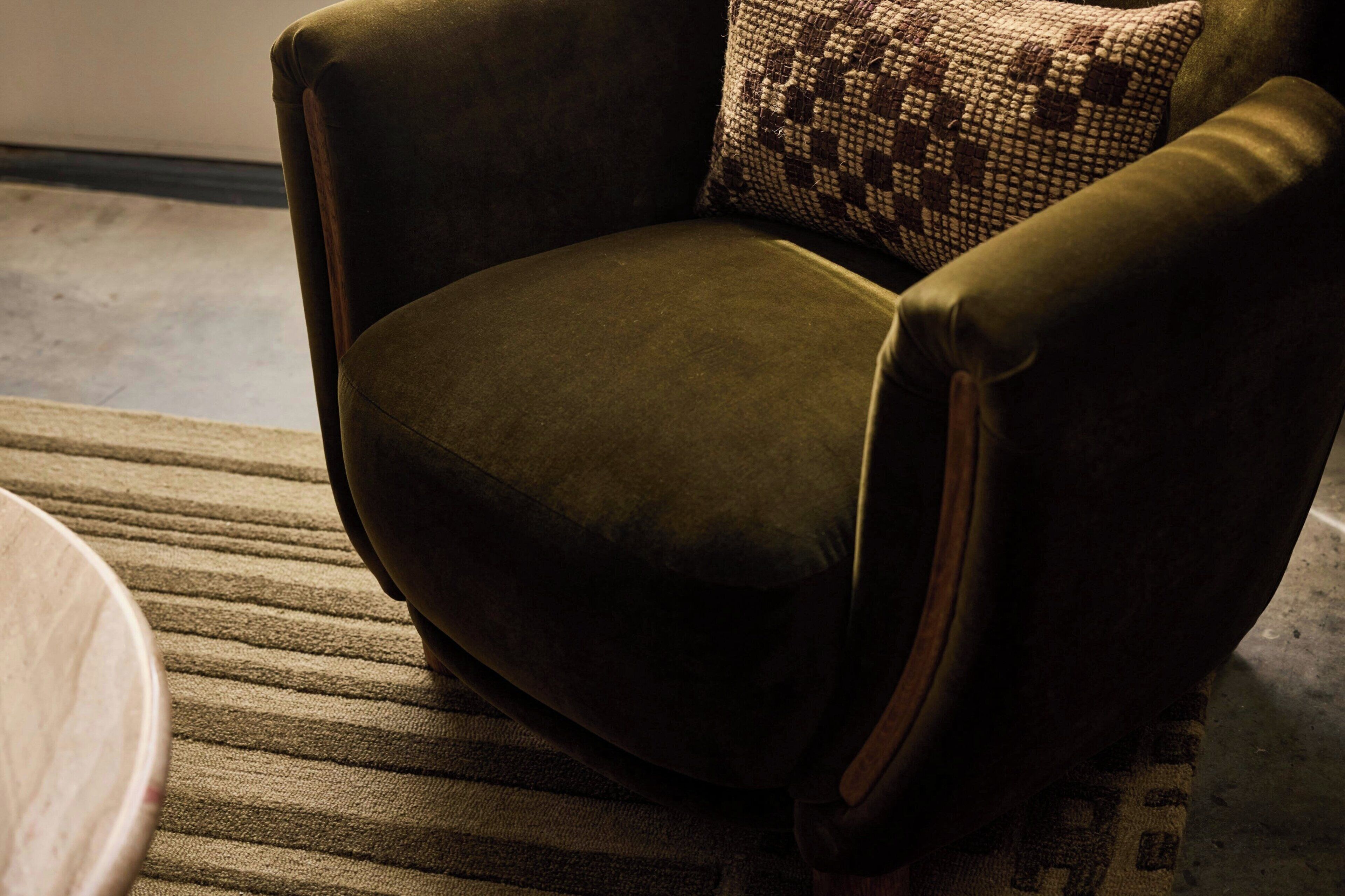 A dark green armchair with a patterned cushion, positioned on a striped rug.