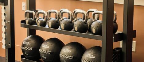A rack with kettlebells and medicine balls labeled with weights.