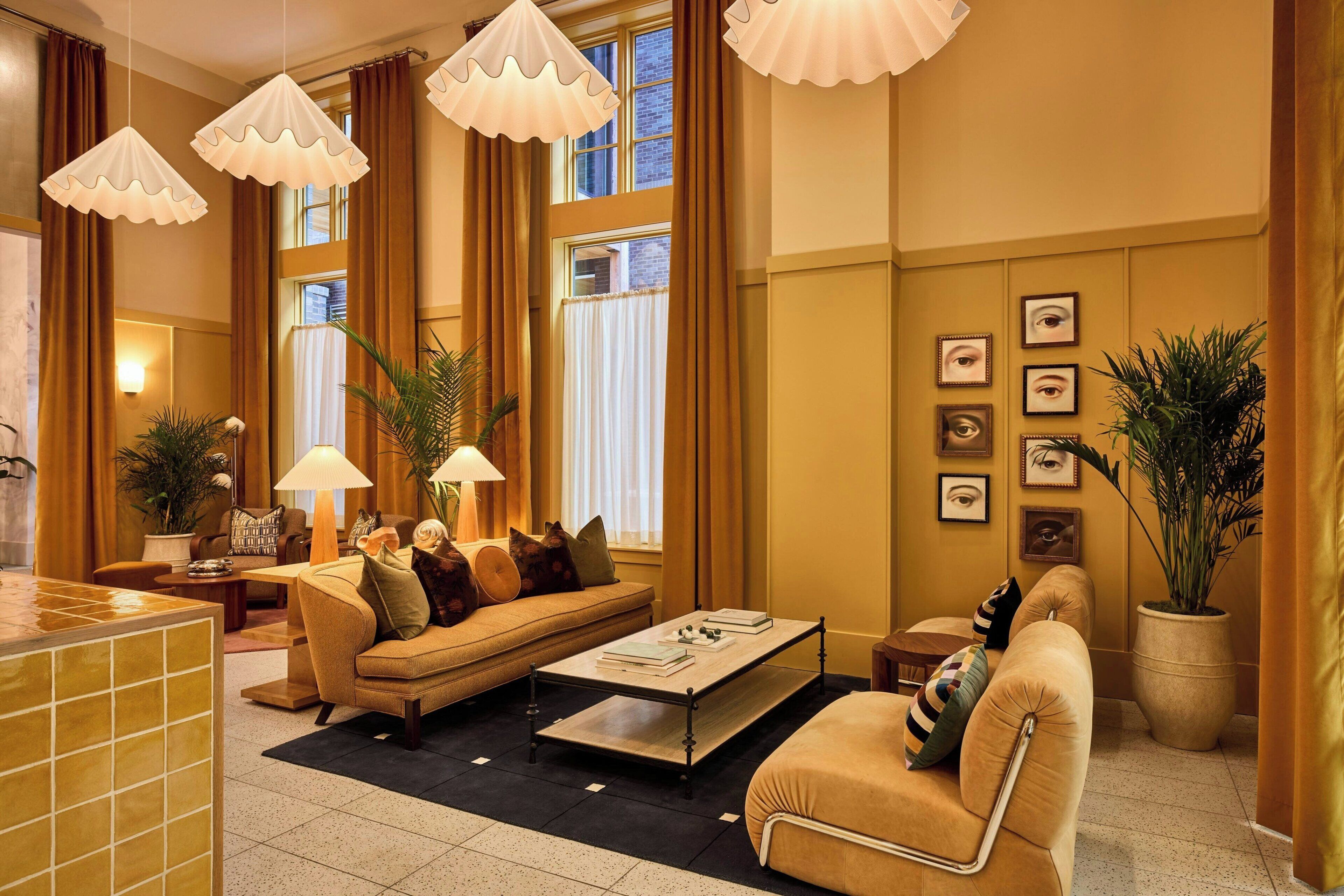 Un salon spacieux comprenant un canapé, des fauteuils, une table basse et une grande fenêtre avec des rideaux.