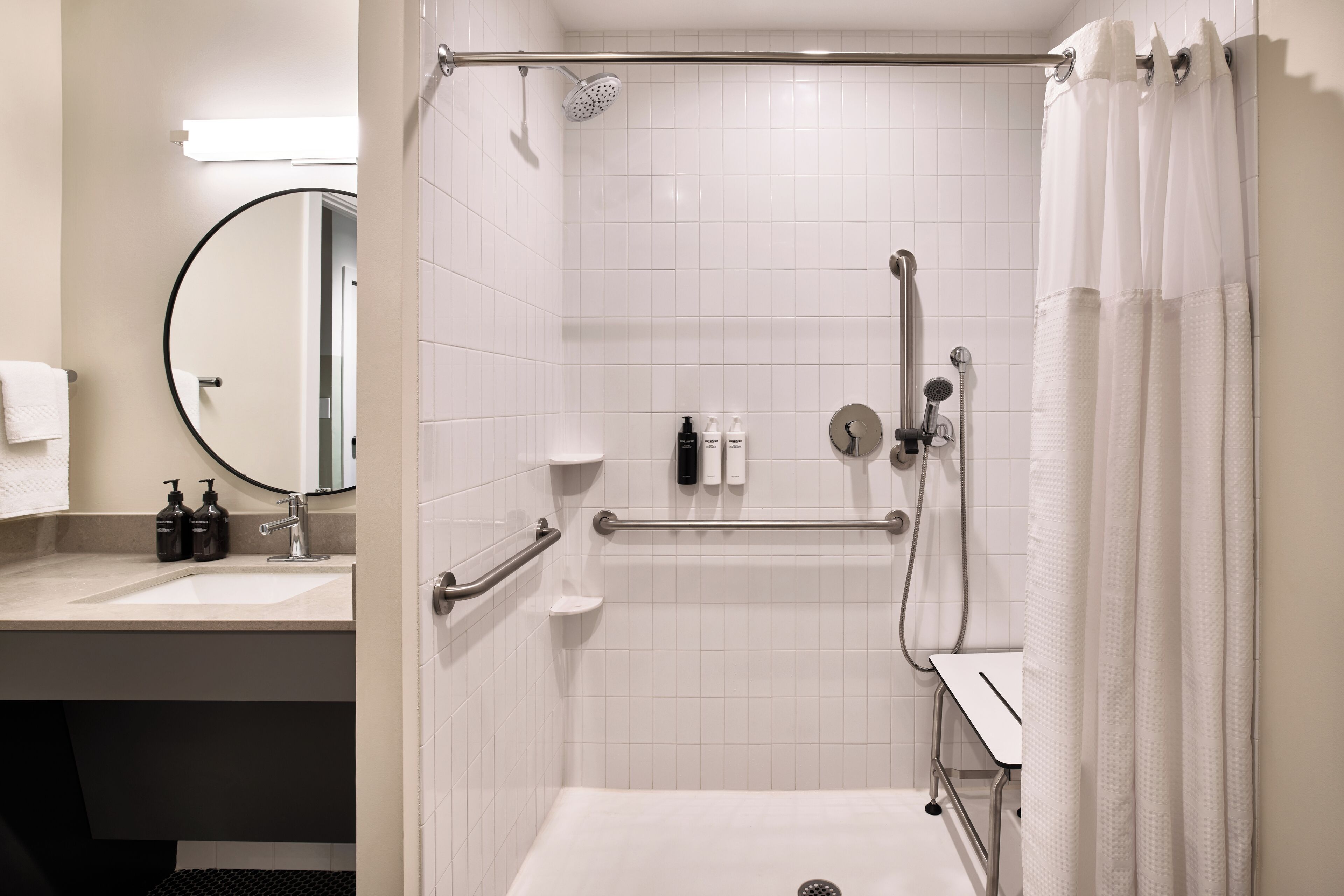 Un baño moderno con ducha, lavamanos y espejo.
