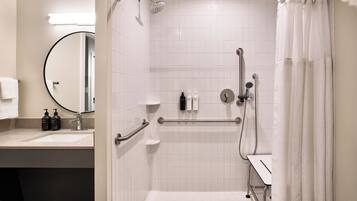 Un baño moderno con ducha, lavamanos y espejo.