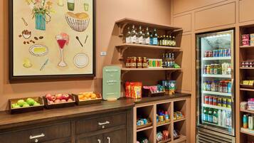 A well-organized kitchenette with a variety of food items, a refrigerator stocked with beverages, and a welcome sign.