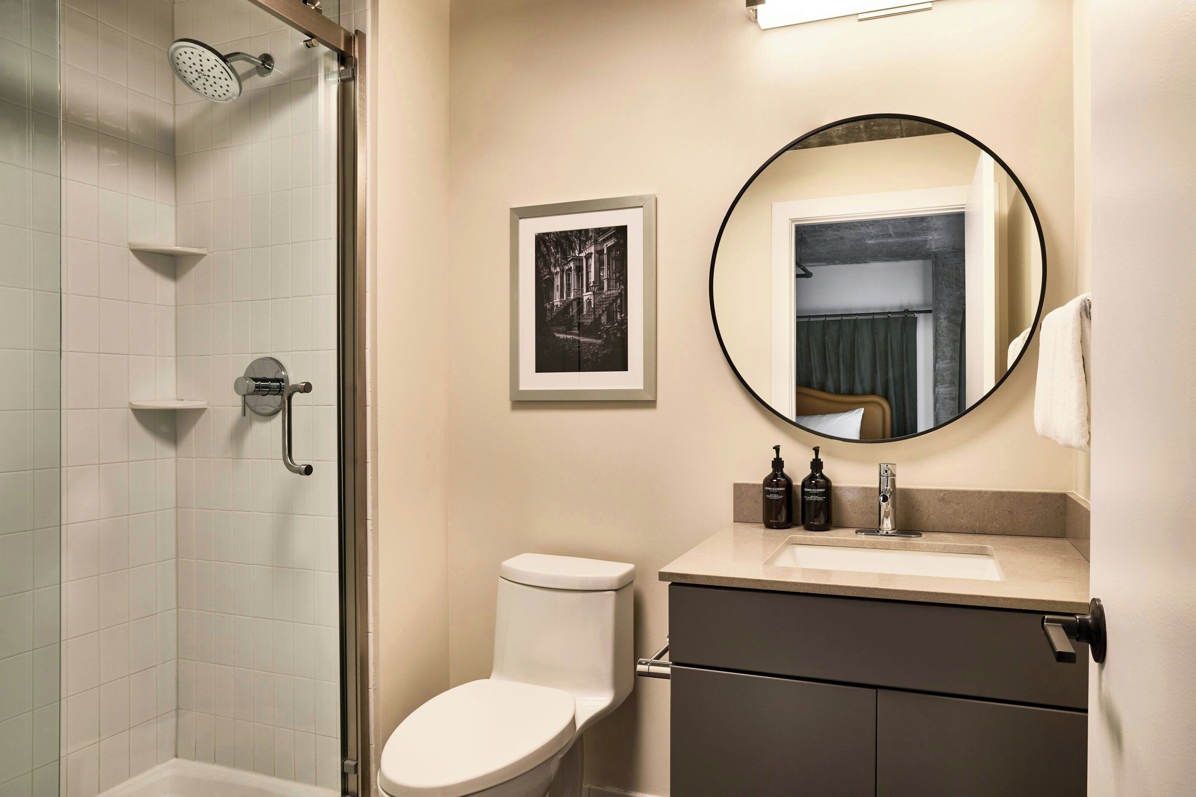 A modern bathroom with a shower, toilet, sink, and a framed picture on the wall.