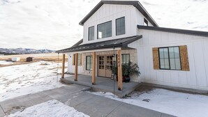 Une maison à deux étages dotée d’un porche abrité, de fondations en pierre et de grandes fenêtres.