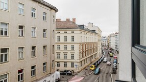 Une vue de rue avec des bâtiments, des véhicules et un passage piéton.