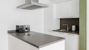 Une cuisine moderne équipée d’un four à micro-ondes encastré, d’une plaque de cuisson et d’un évier.