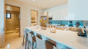 A modern kitchen with a central island, bar stools, and a glass-enclosed shower area.