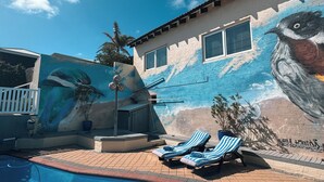 A swimming pool with lounge chairs and a mural of a bird on the adjacent wall. - Beachfront apartment with pool, 4 minutes walk to Indian Ocean. Sleeps 6 (Quinns Rocks)