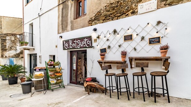 A café with outdoor seating, a signboard, and potted plants.