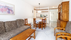 A living room with a sofa, a wooden coffee table, and a dining area with a table and chairs.